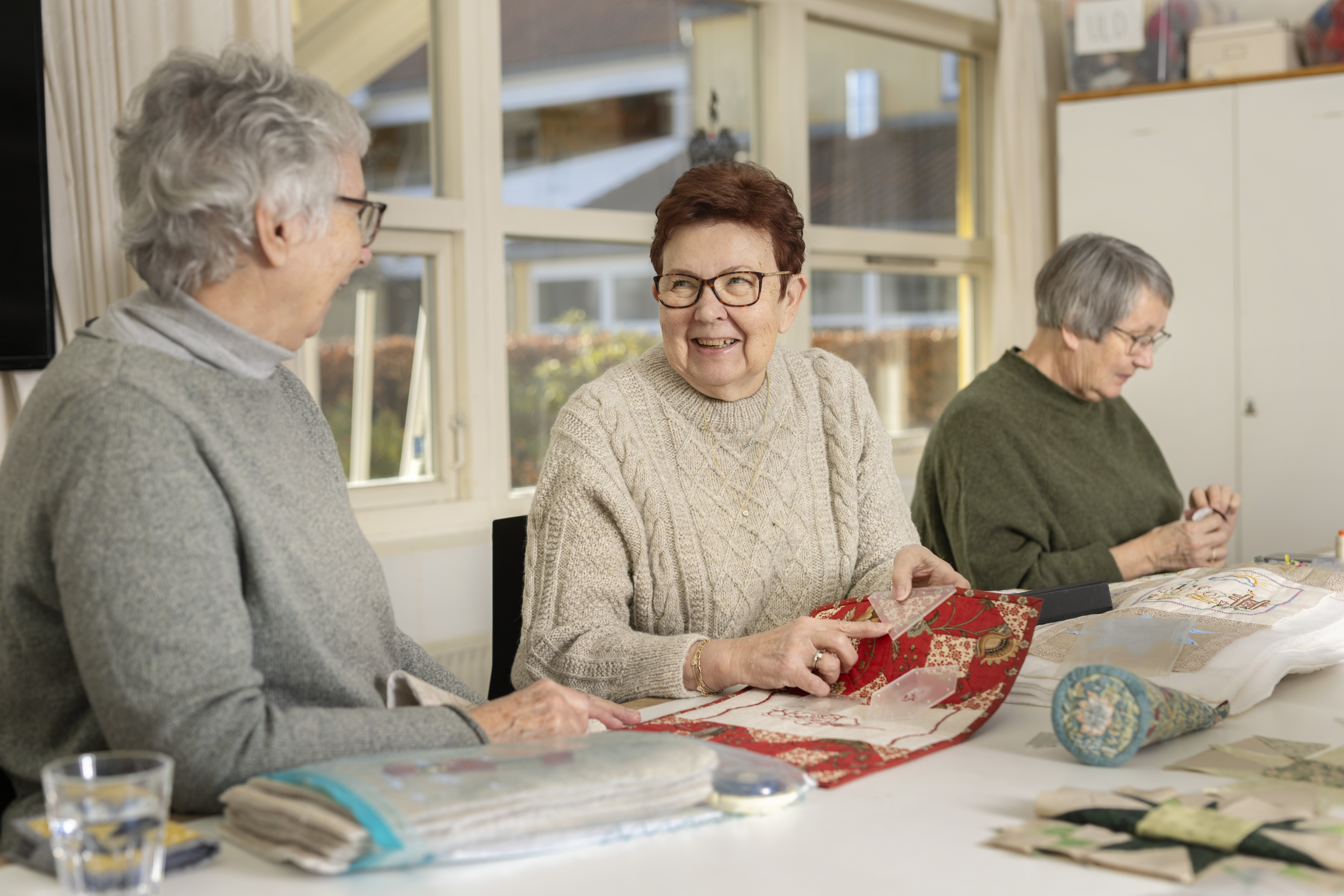 Tre damer der laver patchwork